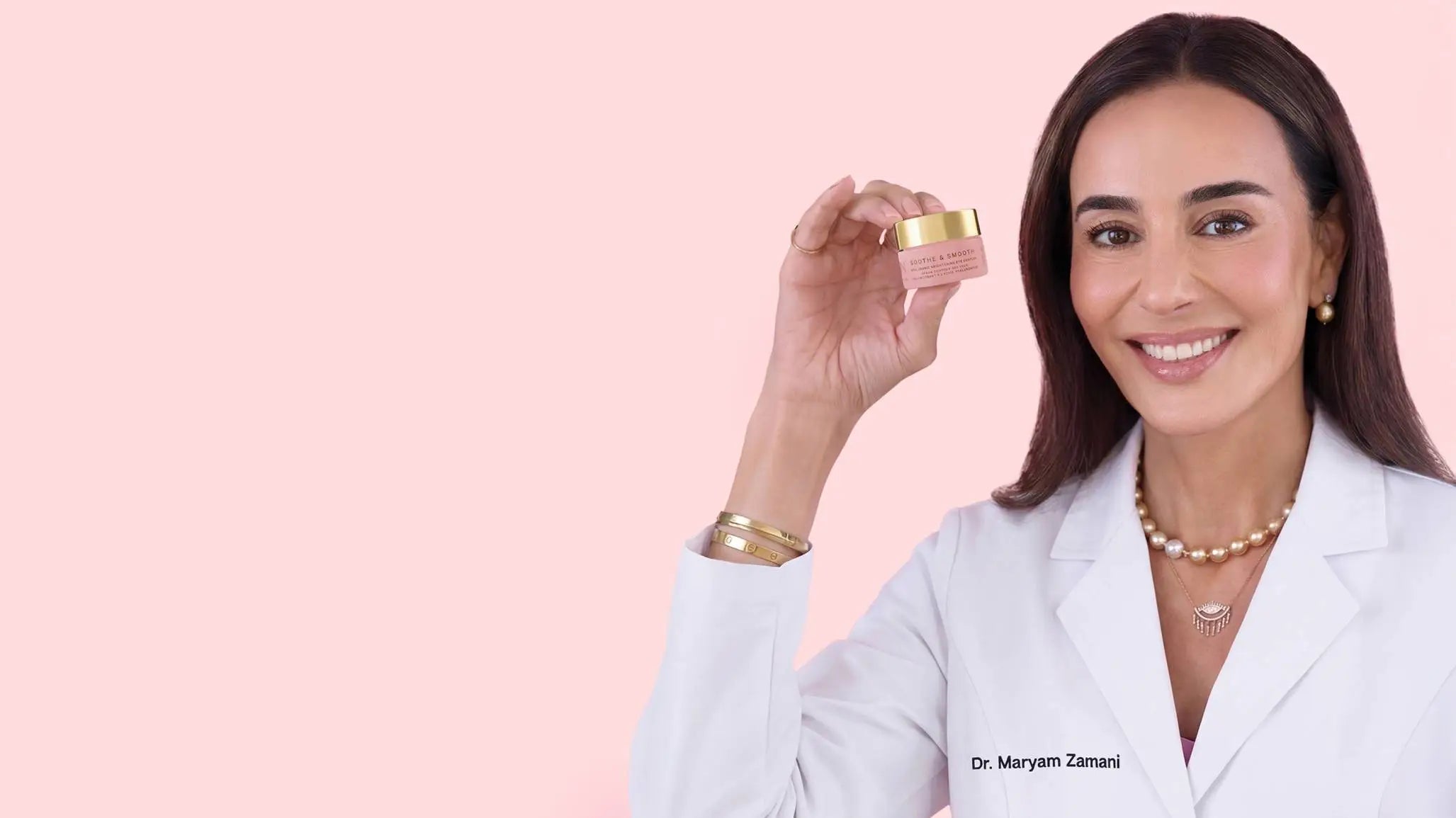 Woman in a white coat holding a small container against a pink background